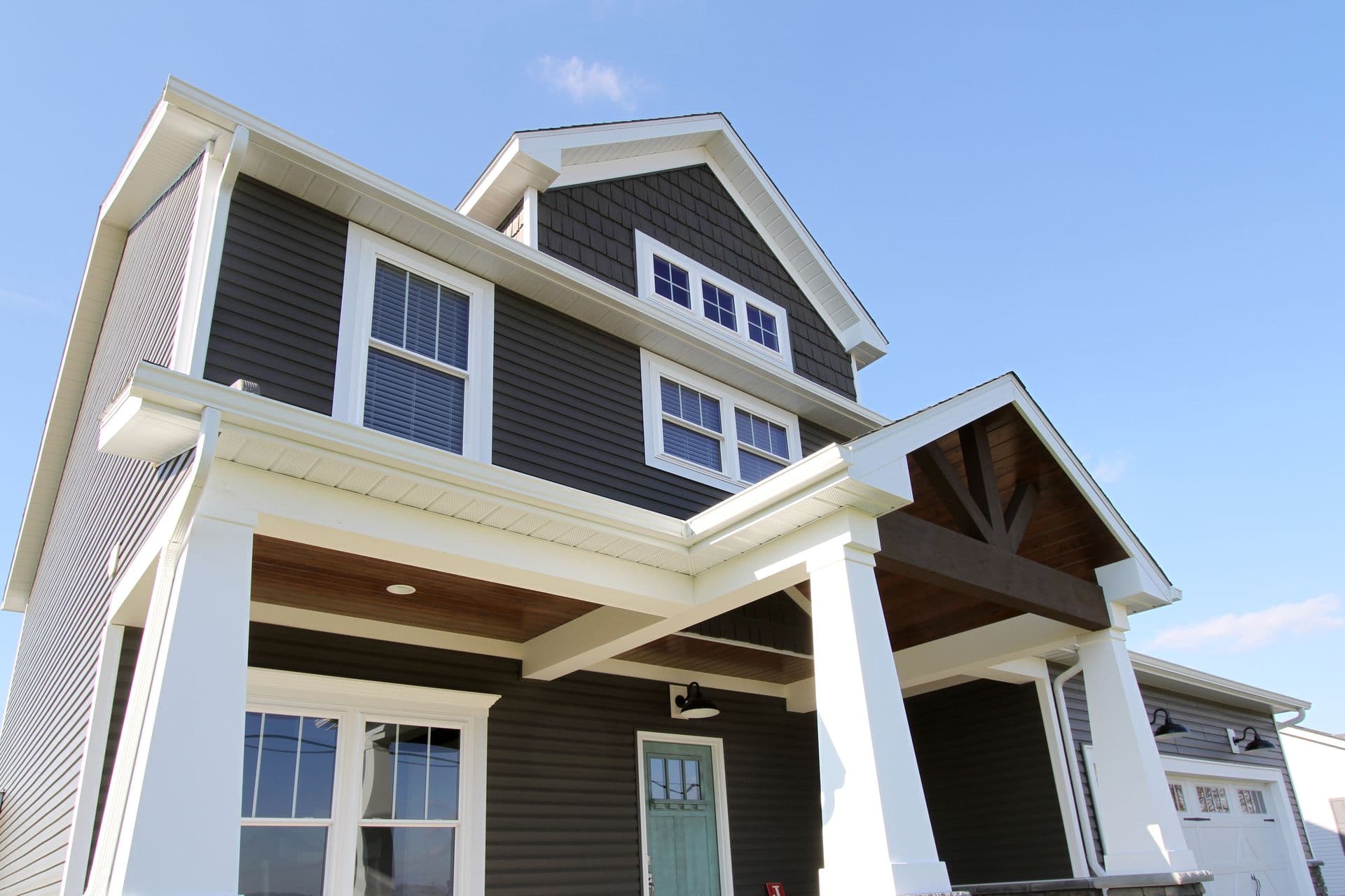 Upper view of house with grey siding, teal door, and multiple windows